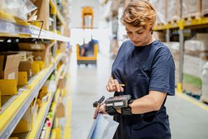 Woman reading a device in bewteen aisles in a retail logistics fulfilment center